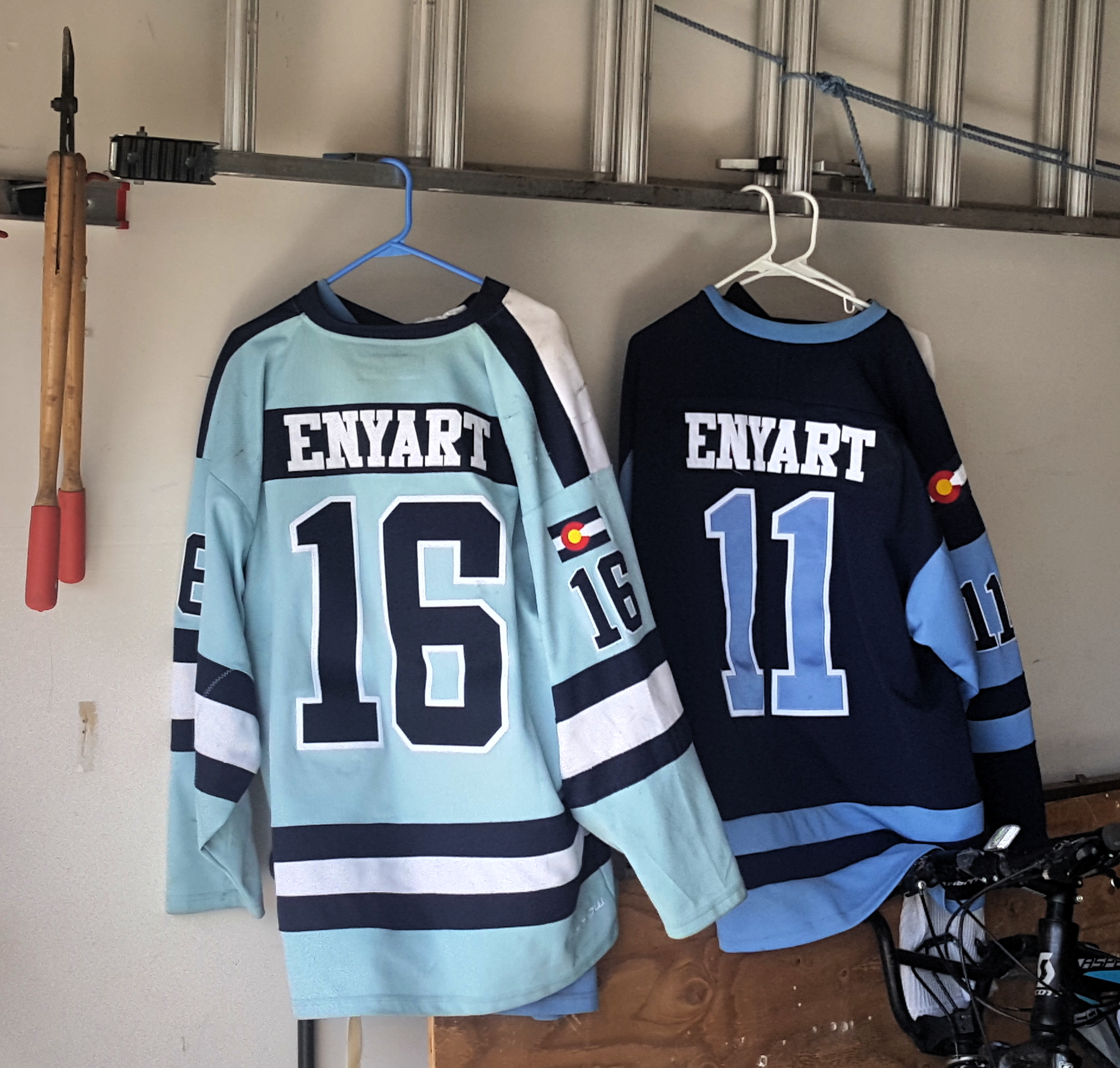 1611 KJV Debate photo of Enyart sons hockey jerseys, #16 & #11, handing in the garage